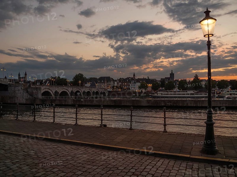 Riverbank at dusk with a street lamp and a cobblestone walkway, Maastricht, limburg, the netherlands