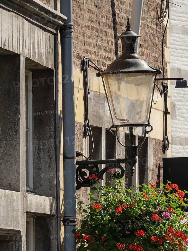 Detailed view of an old building façade with hanging lamp and blooming flowers, Maastricht, limburg, netherlands