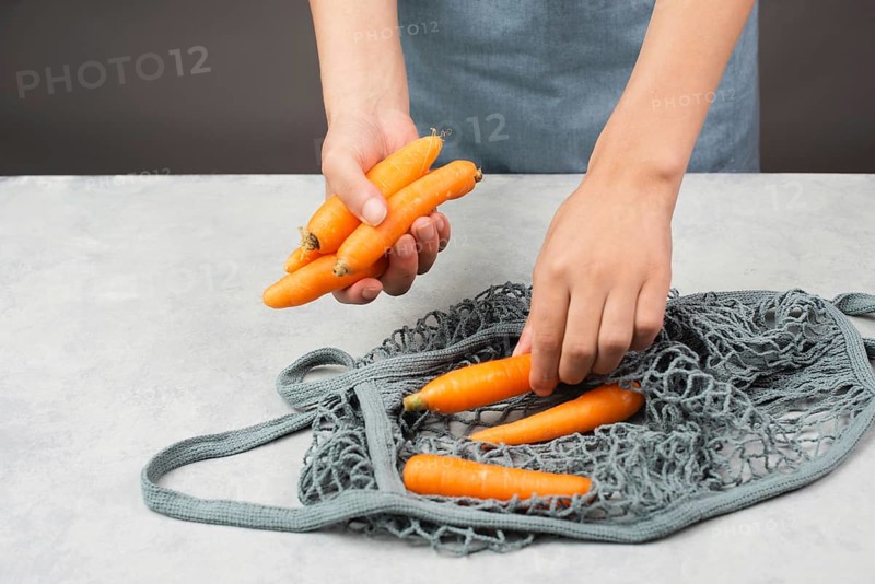 Unpack fresh carrots from a reusable grocery mesh bag, vegetables from the market, healthy food and zero waste