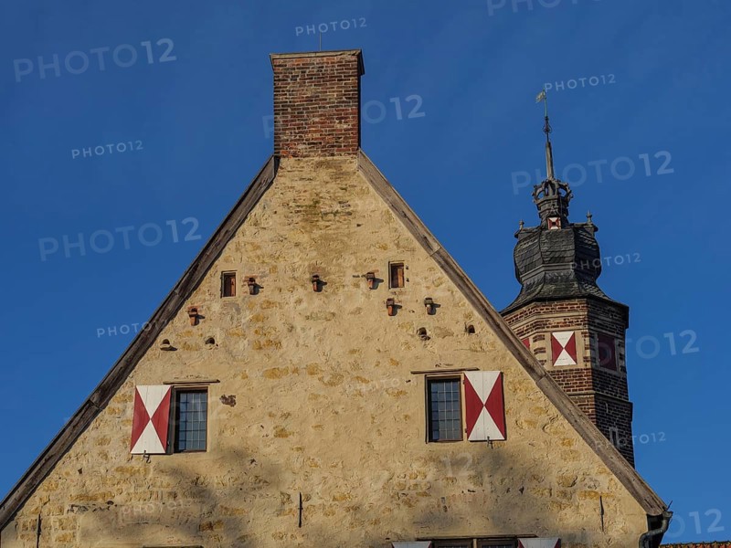 Historic building with crenellated tower and red tiled roof, under a clear blue sky, lüdinghausen, westphalia, germany