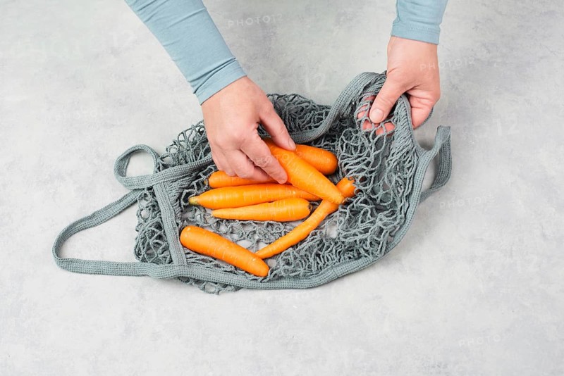 Unpack fresh carrots from a reusable grocery mesh bag, vegetables from the market, healthy food and zero waste