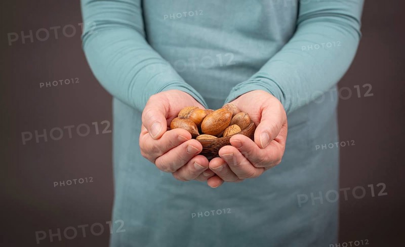Holding a handful of nuts, mix variety of almonds, hazelnuts and pecan nuts, healthy food and lifestyle