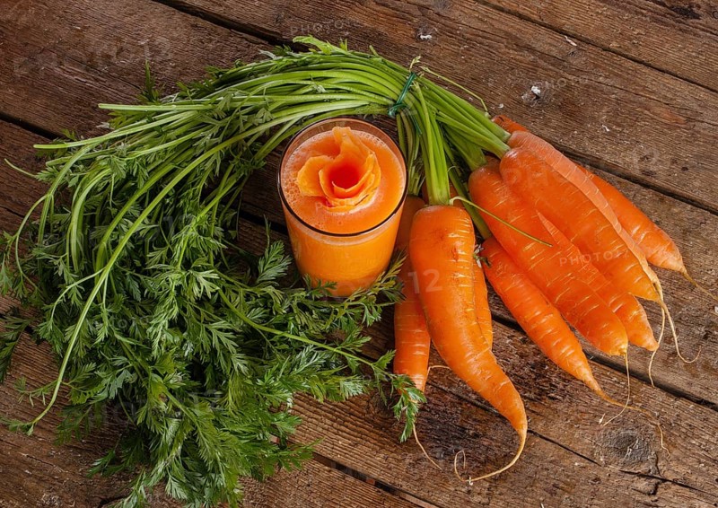 Fresh carrot juice glass with fresh organic carrots on wooden table