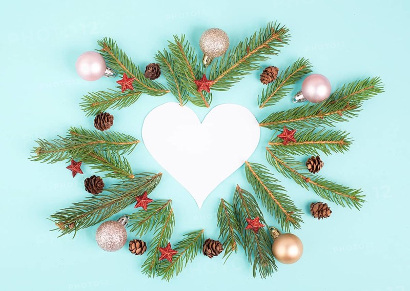 Christmas holiday background in heart shape, frame with fir branches, baubles and pine cones, winter season greeting card