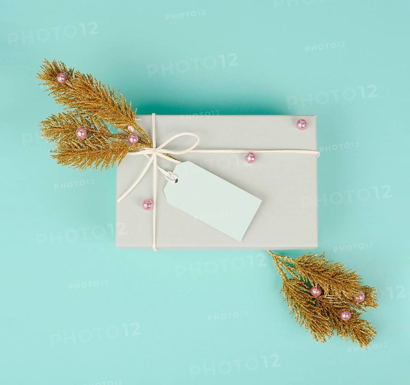 Gift box with a blank tag, golden colored fir branches and baubles, christmas holiday in winter