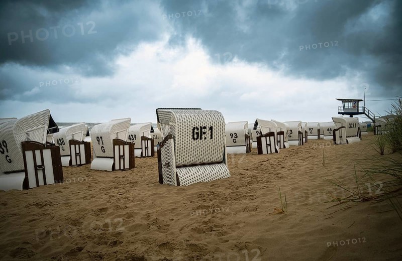 Roofed wicker beach chairs at the baltic sea beach, coast at the island of Usedom in Germany, storm and rain over the brackish water, high waves, storm warning