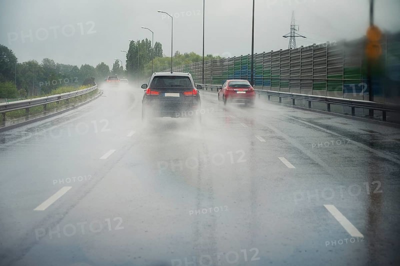 Cars driving on the road, heavy rain, low visibility, slippery street, dangerous storm, overcast weather