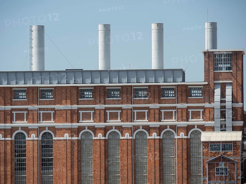 Large red brick building with several large chimneys and many windows under a blue sky, Lisbon, portugal