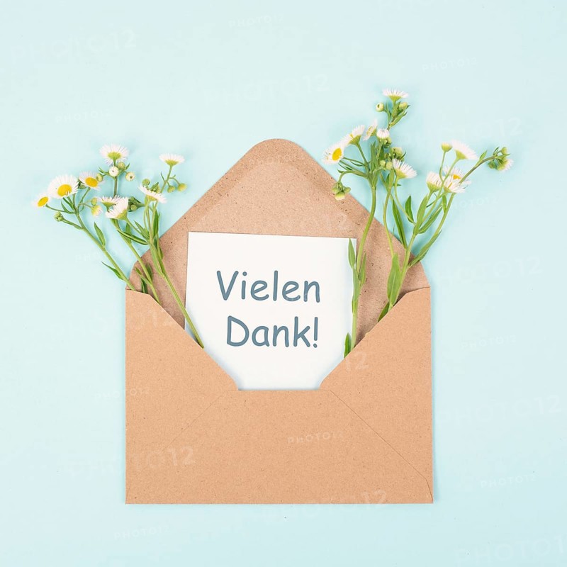 Thank you card in an envelope surrounded by flowers, being thankful, support, help and charity concept, positive attitude, german language