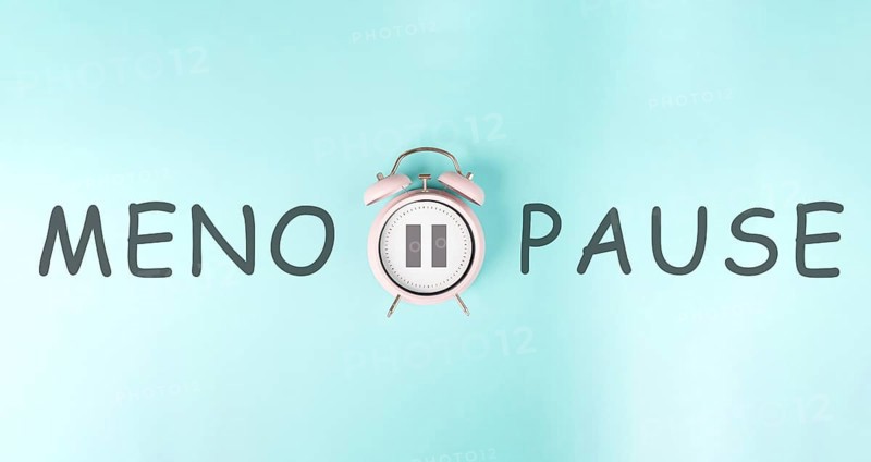 Alarm clock with pause sign and the word menopause, hormone replacement therapy