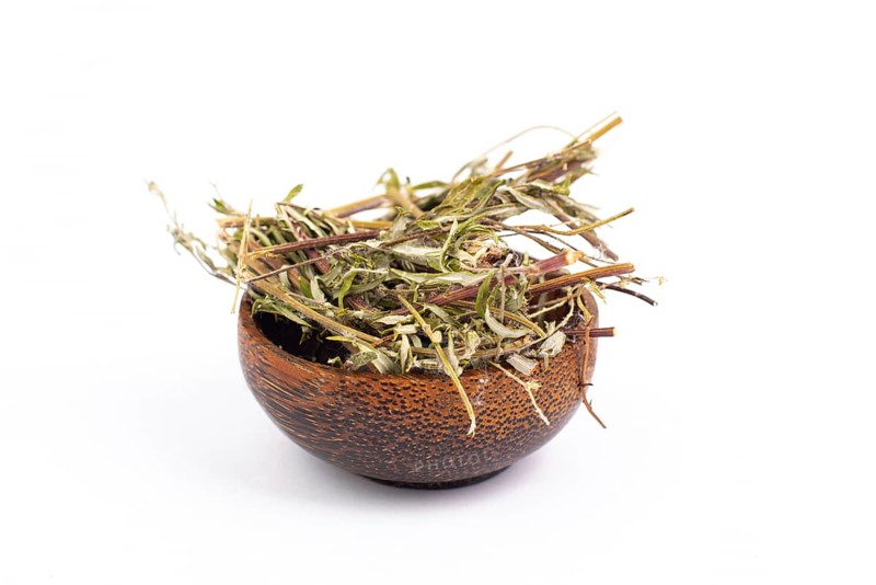 Mugwort or biboz leaves and twigs in a bowl isolated on a white background, dry herb for tea, alternative medicine
