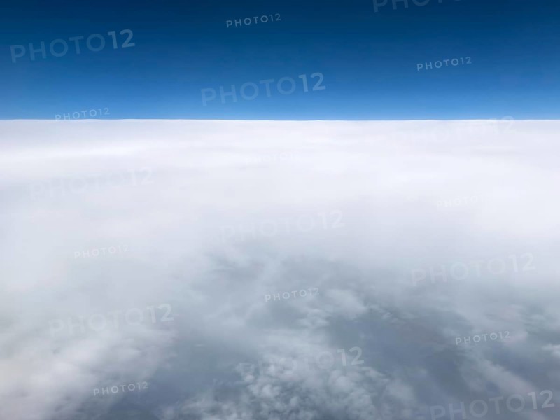 Aerial view View from high altitude 35000 feet around 10700 metres 11 kilometres from above to the rear closed cloud cover of altostratus clouds in the foreground loosening clouds with altocumulus and stratocumulus cluster clouds, above blue sky, international
