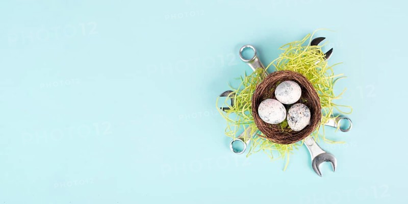 Easter eggs in a bird nest, wrenches and green grass, holiday greeting card with repair tools, spring season