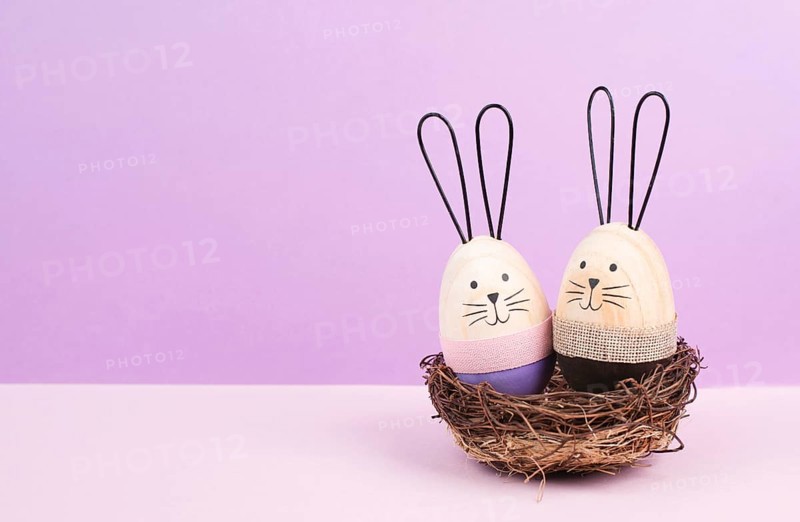 Easter bunny or rabbit couple cuddle together in a wicker nest, wooden egg, spring holiday greeting card