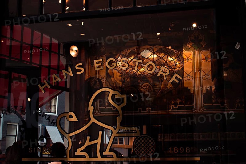 Retro shop window with gold-coloured lion emblem, stylised windows and ornate vintage-style lettering, Amsterdam, Netherlands
