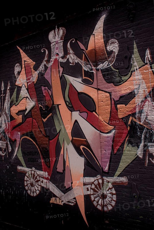 A colourful graffiti on a black brick wall with abstract shapes and a crown, Amsterdam, Netherlands