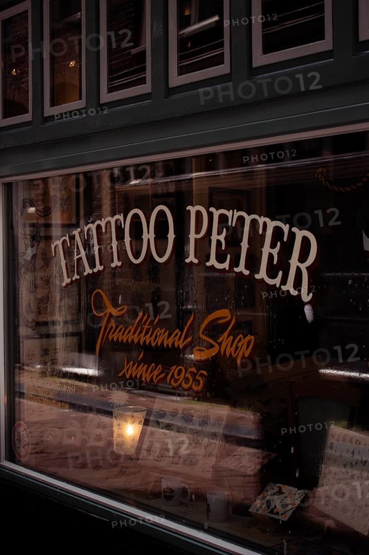 A traditional tattoo shop with a retro sign and nostalgic atmosphere, seen from the outside, Amsterdam, Netherlands