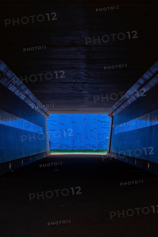 A tunnel with blue lighting ends in an exit with a water landscape and the inscription Waterland, Ilpendam, Netherlands