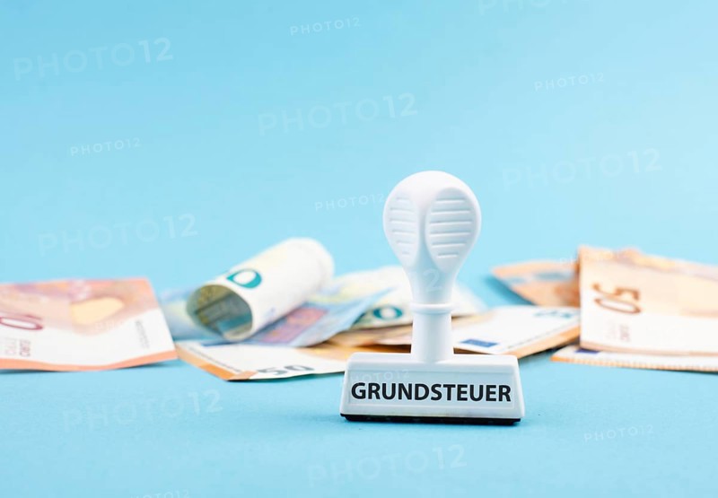 Euro banknotes and a stamp with the german word forr property tax, new law in Germany on houses
