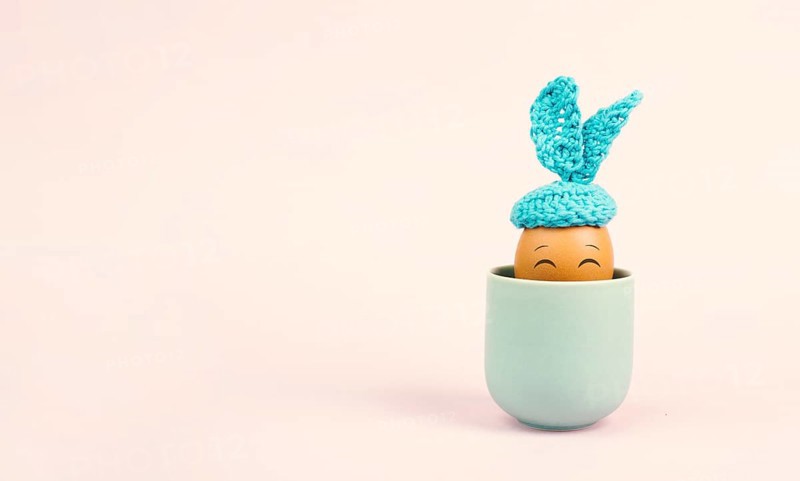 Cute easter bunny or rabbit with a smiling egg face in a cup, spring holiday, greeting card