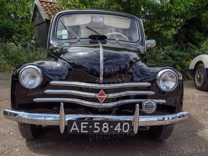 Black vintage car in a forest, showing the front view with licence plate and chrome grill, winterswijk, gelderland, the netherlands