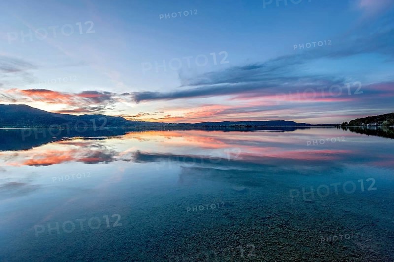 Lake Kochel with reflection of sun and clouds at sunset, calm water, in the background the mountains Heimgarten, Stein, Rötelstein, Hohentanne, Hirschberg, Bromberg and Kreuzbichl, Kochel am See, Bavarian Prealps, Alps, Upper Bavaria, Bavaria, Germany, Europe