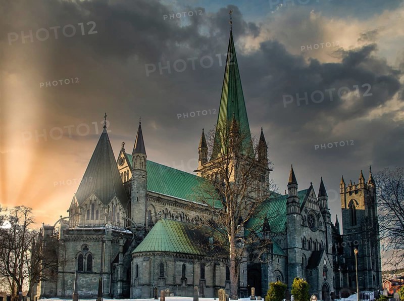 Nidaros Cathedral in Trondheim, Norway during sunset with sun flare and cloudy sky