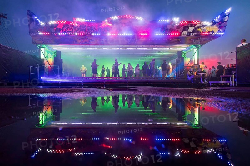 A bumper car with dancing visitors is reflected in a puddle at the Melt Festival in Ferropolis on 12 July 2024. After a total of 27 years, the festival will take place for the last time in 2024