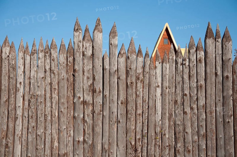The wooden fence of sharpened logs timber