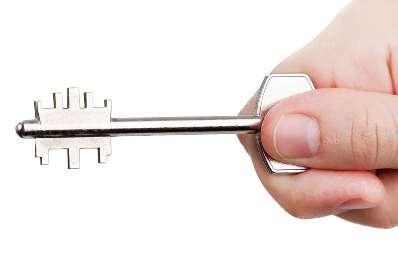 Human hand holding steel metal house door lock key