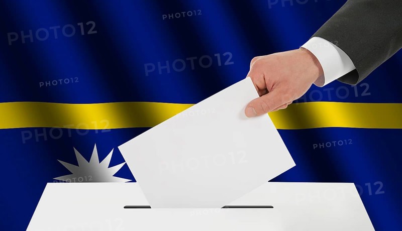 The Nauru flag and the hand with the bulletin about the ballot box