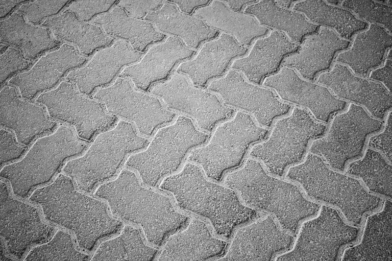 An interlocking pattern of grey paving stones forming a textured brickwork pavement, Concrete floor