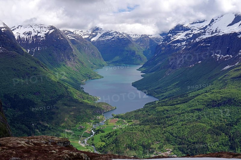 Far-reaching view of a lake between snow-capped mountains and green forests, Lovatnet, Loen, Nordfjord, Norway, Europe
