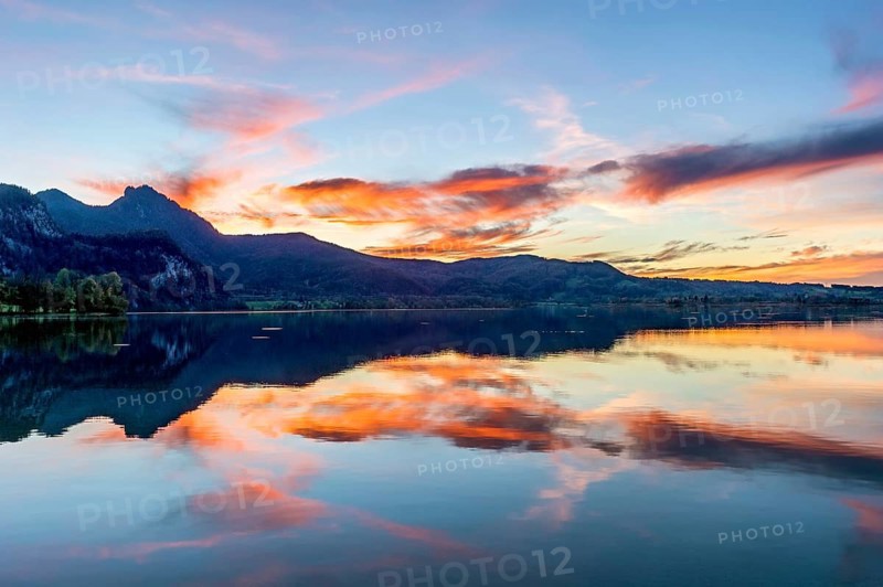 Lake Kochel with reflection of sun and clouds at sunset, calm water, behind the mountains Stein, Rötelstein, Hohentanne, Hirschberg, Bromberg and Kreuzbichl, Kochel am See, Bavarian Prealps, Alps, Upper Bavaria, Bavaria, Germany, Europe