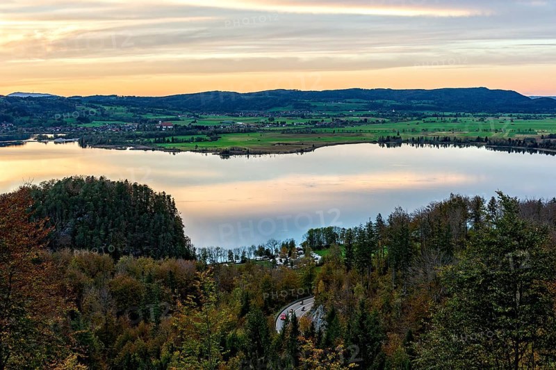 View from the Kesselberg to the Lake Kochel, motorcyclist on the Kesselberg road, Kesselberg pass, sunset, reflection in the water, Bavarian Prealps, Alps, Upper Bavaria, Bavaria, Germany, Europe