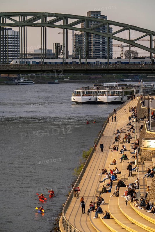 Rhine promenade, Rhine boulevard, on the Deutz bank, people sitting in the spring sun on the Rhine, Hohenzollern railway bridge, Cologne North Rhine-Westphalia, Germany, Europe