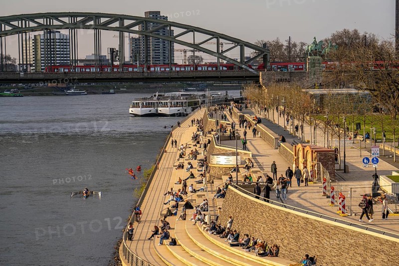 Rhine promenade, Rhine boulevard, on the Deutz bank, people sitting in the spring sun on the Rhine, Hohenzollern railway bridge, Cologne North Rhine-Westphalia, Germany, Europe