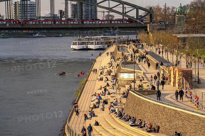 Rhine promenade, Rhine boulevard, on the Deutz bank, people sitting in the spring sun on the Rhine, Hohenzollern railway bridge, Cologne North Rhine-Westphalia, Germany, Europe