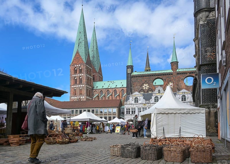 Lubeck, Germany, April 10, 2022: Arts and crafts market with tents and stalls in the city center at the town hall and St. Mary's Church, blue sky with clouds, copy space, Europe