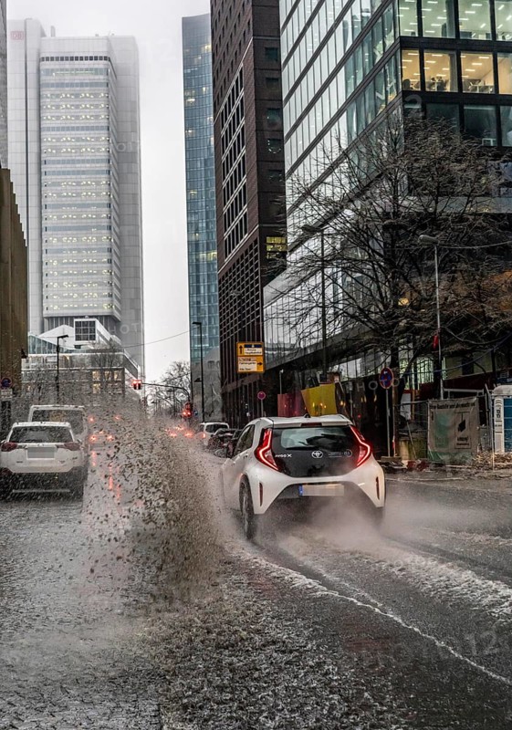 Winter, rainy weather, freezing rain, large puddle, puddle of water, in the city centre, Grosse Gallusstrasse, vehicles driving through, spraying water fountains, Frankfurt am Main, Hesse, Germany, Europe