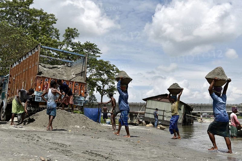 Labourer carries extracted sand from Beki River, in Barpeta district in Assam, India on Sunday September 2, 2018. Sand extraction from rivers, essential for construction and infrastructure, significantly impacts the environment by destroying aquatic habitats, increasing riverbank erosion, degrading water quality, depleting groundwater, and altering natural flow patterns