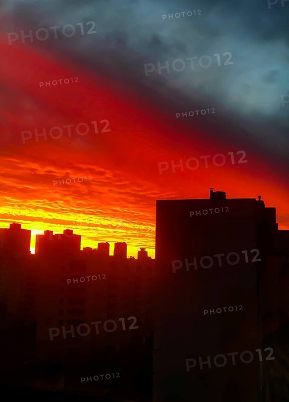 Fiery sunset casting silhouettes of buildings against a dramatic orange and dark sky.Belarus, Minsk