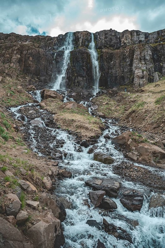 Idyllic waterfall Budareyrarfoss with river at Seydisfjordur, Iceland, vertical shot, Europe