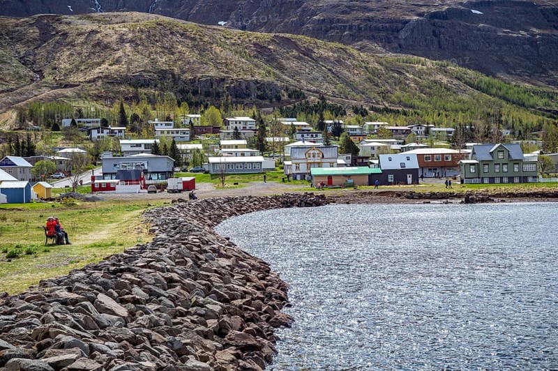 Residential area with residential buildings and houses behind a lake in front of a mountain in Seydisfjordur, Iceland, Europe