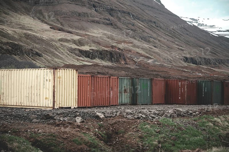 Colorful export import cargo shipping container standing next to each other next to the road at Seydisfjordur, Iceland, wide angle shot, Europe