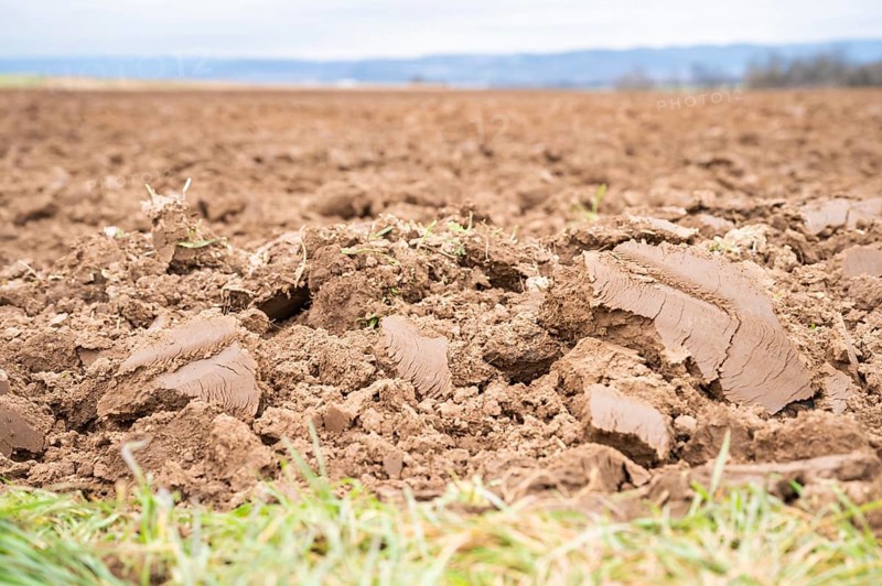 Topsoil brown soil on an agricultural field view from low angle, focus on foreground during cloudy day