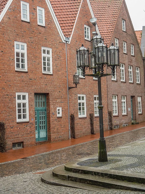 Quiet old square with brick houses and historic lanterns on cobblestones, stade, germany