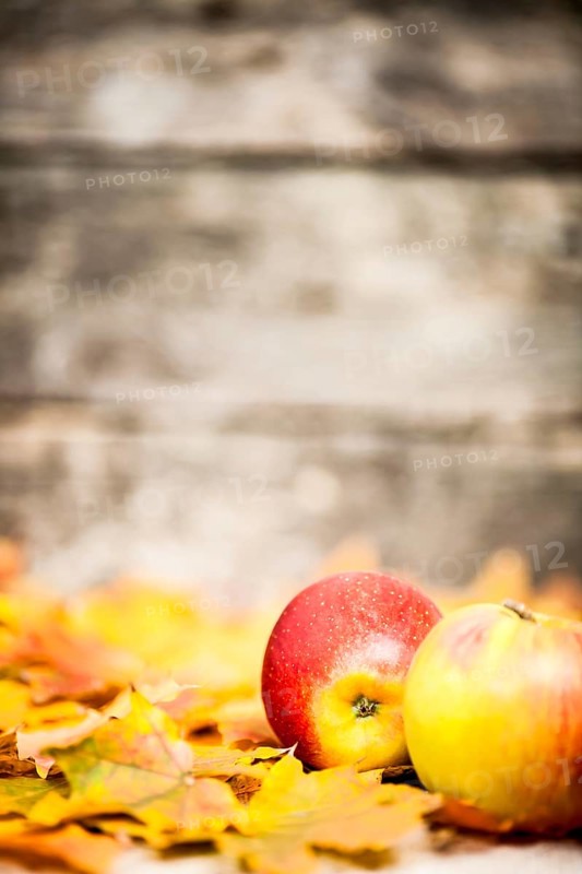 Autumn border from apples and maple leaves on old wooden background