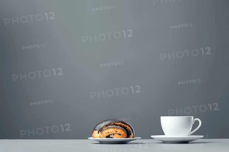 White mug and a chocolate muffin with poppy seeds on a gray background