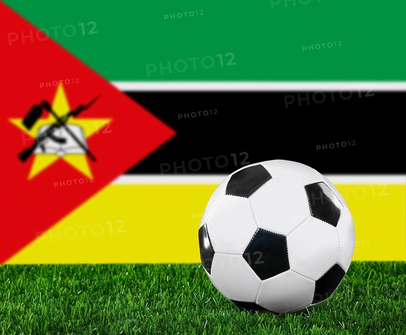 The Mozambique flag and soccer ball on the green grass
